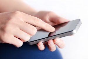 Girl hand touching screen on modern mobile smart phone. Close-up image with shallow depth of field focus on finger.